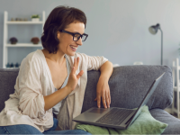 person sitting on a couch waving to their laptop computer